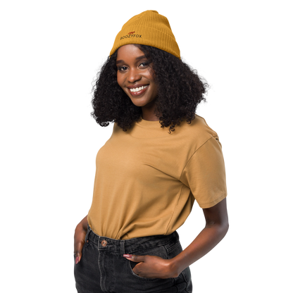 Smiling woman wearing a Mustard Yellow Organic Ribbed Beanie With An Embroidered Boozy Fox Logo On Fold - Shop Organic Cotton Beanies Online - Boozy Fox