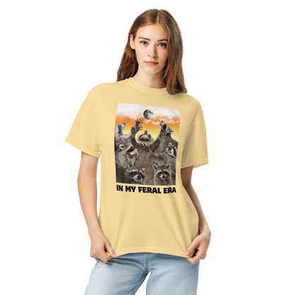 Woman wearing a Funny In My Feral Era Raccoon heavyweight graphic t-shirt in butter yellow by Boozy Fox