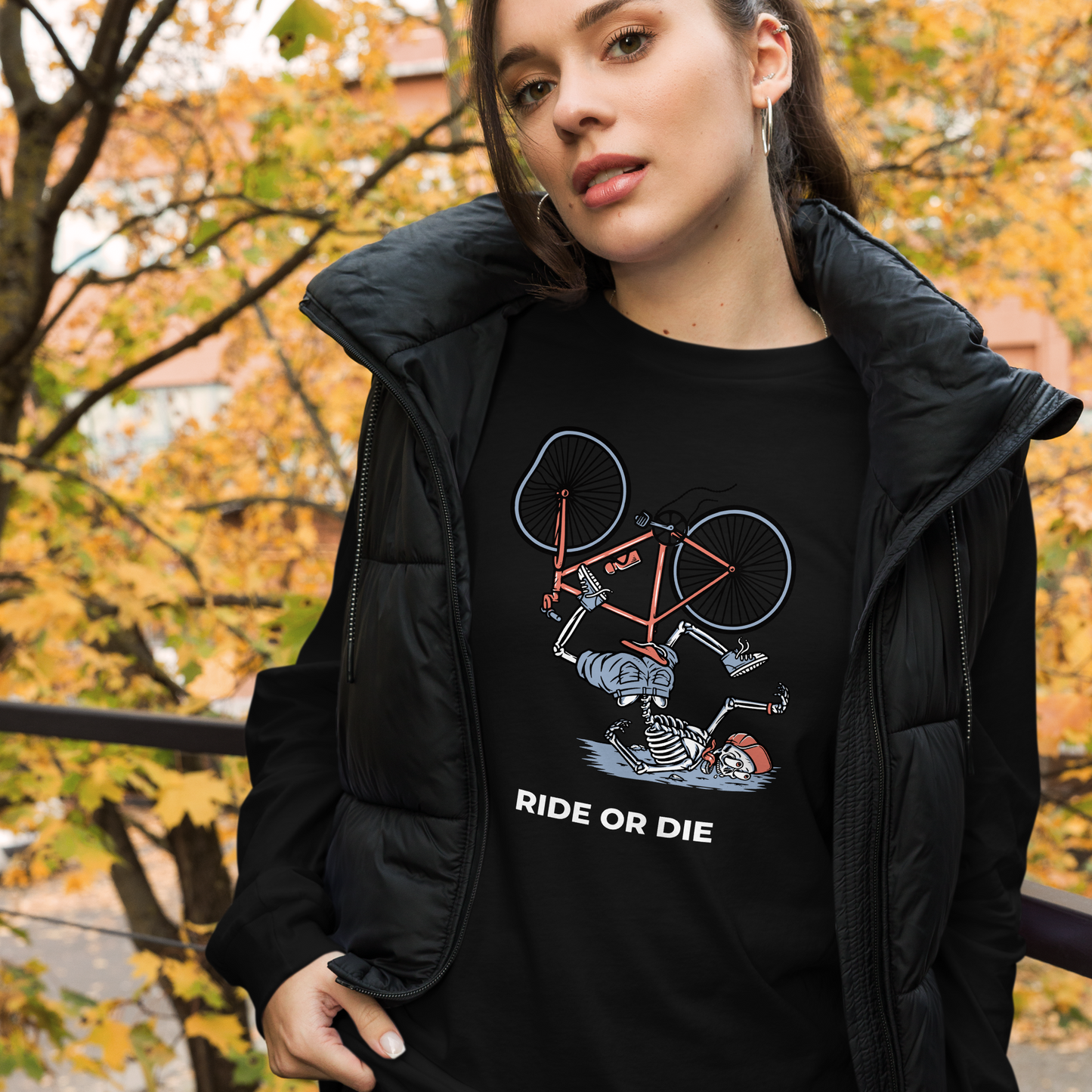 Woman wearing a Black Ride or Die Long Sleeve Tee featuring a bold Skeleton Falling While Riding a Bicycle graphic on the chest - Funny Skeleton Long Sleeve Graphic Tees - Boozy Fox