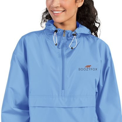 Smiling Woman Wearing a Light Blue Champion Packable Jacket featuring a sleek embroidered Boozy Fox logo on the chest - Waterproof Champion Windbreakers & Raincoats - Boozy Fox