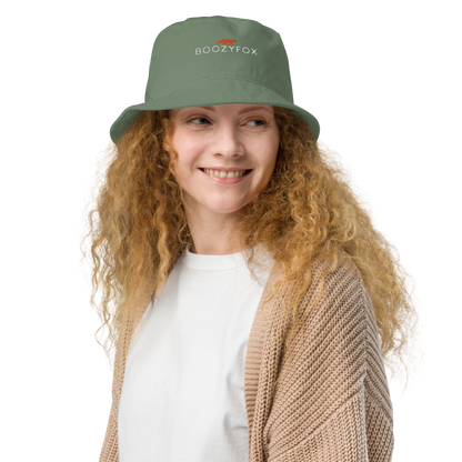 Smiling woman wearing a Dill Green Organic Bucket Hat featuring a recognizable Boozy Fox embroidery logo on the front - Bucket Hats - Boozy Fox